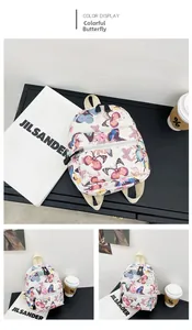 Close-up detail of mini cream canvas backpack with colorful butterfly print and front pocket