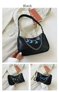 Close-up of black leather underarm bag with blue butterfly charms and silver chain