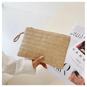 Detail of handmade wheat straw woven clutch featuring herringbone pattern and wrist strap