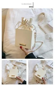Détails d'un sac seau blanc à texture ondulée avec bandoulière chaîne dorée