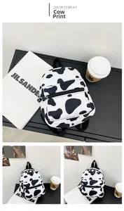 Detail view of mini cow print canvas backpack with front zipper and top handle