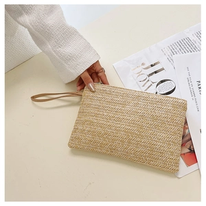 Macro detail of beige straw woven clutch bag with leather wristlet and metal zipper