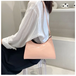Close-up of a pale pink crocodile pattern shoulder bag worn on a woman's shoulder