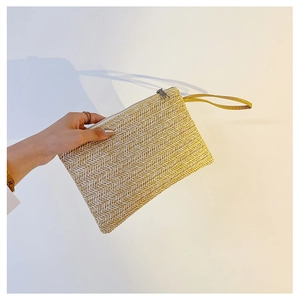 Detailed view of handmade straw clutch bag with V-shaped weave and metal zipper