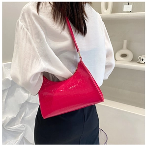 Detail of fuchsia crocodile texture underarm bag with glossy patent finish in a chic setting