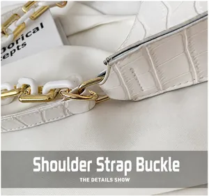 Detail of golden D-ring hardware and white croc-embossed leather strap connection