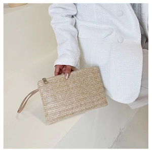 Detail of wheat grass woven clutch bag with gold zipper closure and stylish wrist strap