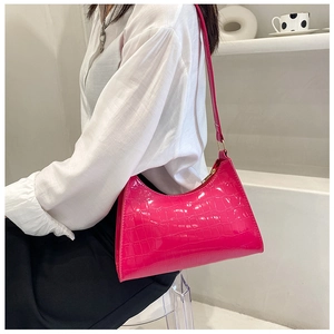 Detail of hot pink crocodile texture leather shoulder bag shown on a model