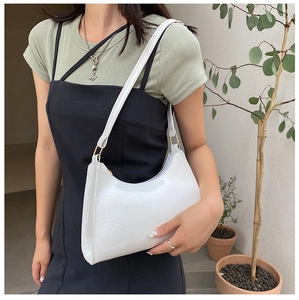 Detail of white crocodile pattern shoulder bag with golden metal hardware and PU leather