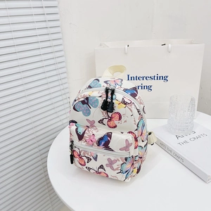 Off-white canvas backpack with colorful butterfly print and double zipper compartments