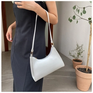 Close-up of white crocodile pattern hobo bag with gold buckle detail and slim strap
