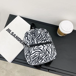 Minimalist black and white cow print canvas backpack for students on a dark aesthetic background