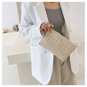 Detail of a handmade wheat straw clutch bag with woven herringbone pattern and wrist strap