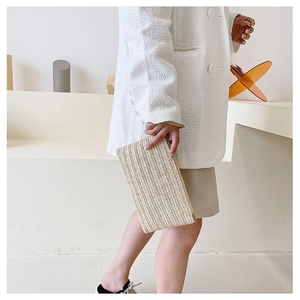 Detail of handmade straw clutch bag with V-shaped weave pattern and metal zipper
