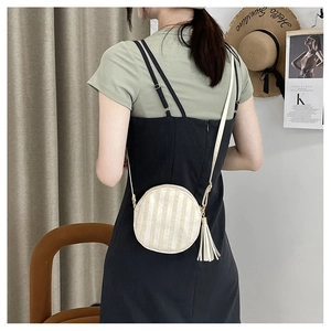 Dettaglio borsa rotonda in paglia con nappe bianche e design estivo a righe per vacanze
