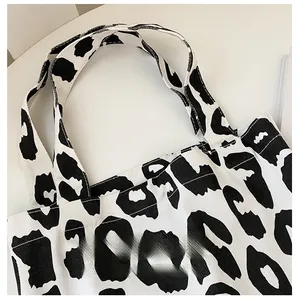Détail de la couture renforcée de la bandoulière sur le sac fourre-tout en toile à motif vache