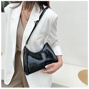 Fashionable black crocodile embossed crescent shoulder bag shown on a model