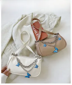 Détail de sacs sous le bras avec chaînes argentées et pendentifs papillon bleus