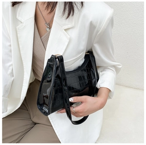 Detailed close-up of glossy black crocodile-patterned underarm bag with sleek moon shape