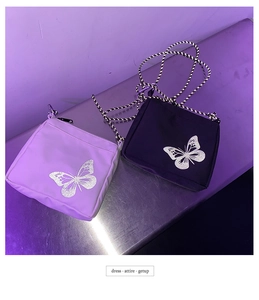 Detail of crossbody bag with reflective butterfly prints and braided ropes in purple lighting