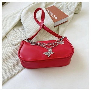 Détail du sac rouge avec des breloques papillon argentées et des chaînes multicouches