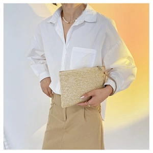 Detail of handmade wheat grass woven clutch bag featuring metal zipper and wristlet strap