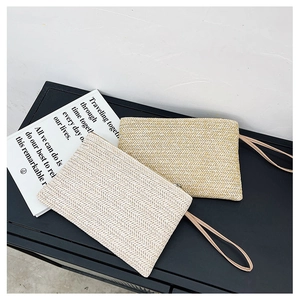 Detail view of woven straw clutch set with zipper closure and wrist strap