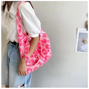 Détail du grand sac cabas en toile à imprimé léopard rose porté par un mannequin