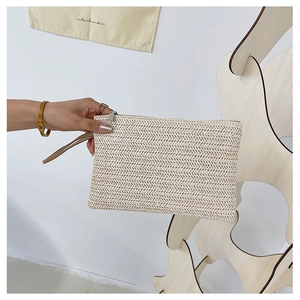 Detail of hand-woven straw clutch bag featuring a V-shaped texture and metal zipper