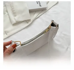 Detail view of the smooth golden zipper on white crocodile texture underarm shoulder bag