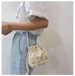 Détail du sac seau tissé beige avec broderie florale et fermeture par cordon de serrage