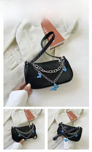 Détail du sac sous le bras noir avec chaîne argentée et pendentifs papillon bleus