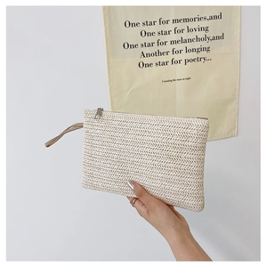 Detail of handmade straw clutch bag with woven herringbone pattern and leather wrist strap