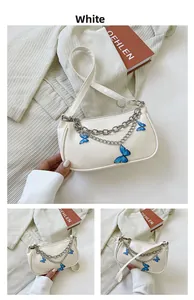 Détail du sac baguette blanc avec chaîne argentée et breloques papillon bleues