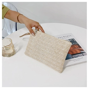 Macro view of woven straw clutch with chevron pattern, silver zipper, and wrist strap detail