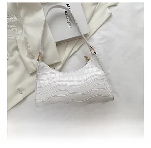 White faux crocodile skin handbag shown next to a smartphone for size comparison