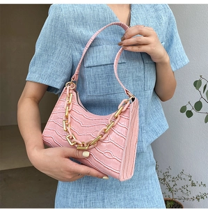 Detail of pink faux crocodile leather baguette bag with thick gold and plastic chain