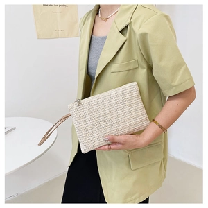 Detail of handmade wheat straw clutch bag with beige herringbone pattern and metal zipper