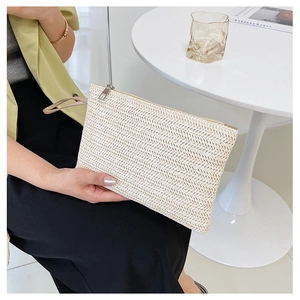 Detail of V-shaped woven straw clutch with a metal zipper and wrist strap in oatmeal