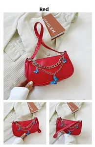 Détail du sac rouge en demi-lune avec des chaînes en métal et des papillons bleus