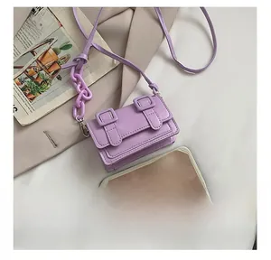 Detail view of mini purple leather crossbody bag next to a smartphone for size comparison