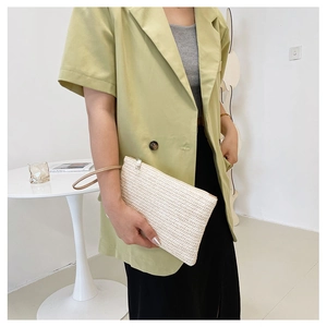Detail of hand-woven wheat straw clutch bag texture and wristlet in cream white