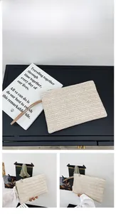 Detail of hand-woven off-white straw envelope clutch with a zipper and wristlet strap