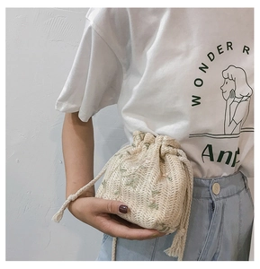 Stroh-Beuteltasche mit Blumenstickerei und weißem Kordelzug im sommerlichen Stil