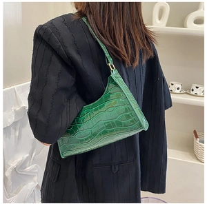 Close-up of bright green crocodile pattern underarm bag on model with black blazer