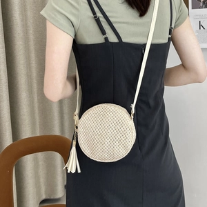Borsa a tracolla rotonda in tessuto beige da donna con nappe indossata da modella
