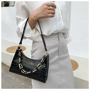 Close-up of black crocodile pattern baguette bag with stylish thick chain and long strap