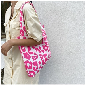 Détail d'un grand sac fourre-tout en toile à motif léopard rose porté avec robe chemise