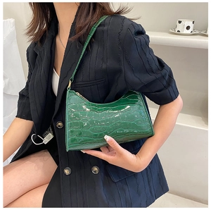 Detailed view of the dark green crocodile pattern shoulder bag on a model's shoulder