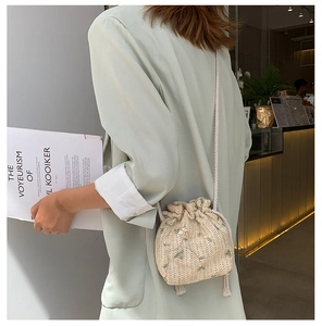 Vue détaillée du sac seau tissé beige avec broderies florales et fermeture à cordon